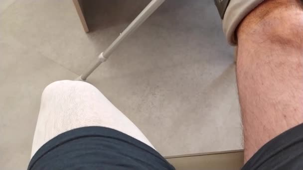 ヨーロッパの男性魔女アキレス腱断裂緊急後のリハビリ医療のための空の待合室で特別な靴や松葉杖で動作した後 病院の待合室に座って — ストック動画