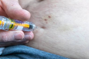 Aşil tendonu olan Avrupalı bir adam, tromboz miyokardiyal enfarktüsü önlemek için karnına enoksiaparin ya da dalteparin enjekte ettikten sonra deri altında prefabrik şırınga ile yırtılır.