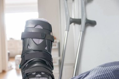 Achilles tendon yırtılması ameliyatından sonra Avrupalı bir adam özel fizyoterapi ayakkabısı ve iyileşmek için koltuk değnekleriyle eve döndü.