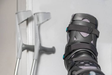 Achilles tendon yırtılması ameliyatından sonra Avrupalı bir adam özel fizyoterapi ayakkabısı ve iyileşmek için koltuk değnekleriyle eve döndü.