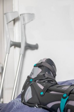 Achilles tendon yırtılması ameliyatından sonra Avrupalı bir adam özel fizyoterapi ayakkabısı ve iyileşmek için koltuk değnekleriyle eve döndü.