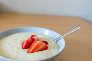Kasede pirinç pudingi olan pek çok çilek gümüş kaşıkla veya lezzetli parmak yiyecekleri ve sürdürülebilir fındık için ahşap mutfak masasında kırmızı meyve ve vitaminli sağlıklı atıştırmalıklar yemeye hazırdır.