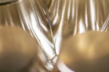 Parlak yansımaları ve harmonik şekilleri olan gümüş ve altın metal yüzeyin soyut altın arkaplan desenli makro modeli. Daireler ve koniler zarif fütürist tasarım grafiksel dalgalar.