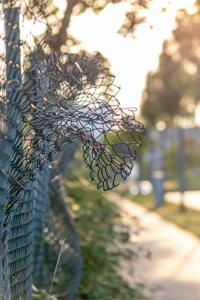 Green damaged wire-mesh fence is ruined after collision with car accident as crushed fence for car insurance and property insurance and loses security and safety with vandalism and barrier demolition