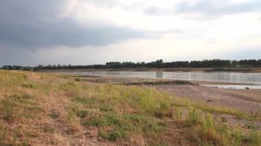 Extreme low water line in river Rhine Dsseldorf in extreme drought with no rainfall causes drying out riverbed and low tide shows global warming and climate change with dry riverbank water shortage