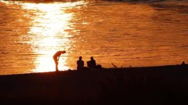 Golden sunset at the beach with men silhouettes relaxing on beach after work with friends and beach party for happiness and golden sunset outdoor adventure atmosphere in peaceful and tranquil evening