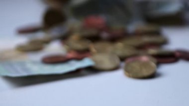 Euro money savings sliding inside glass jar full of Euro coins and Euro banknotes for financial management of pocket money and tip or gratuity for piggy bank currency pile as cash close-up macro view
