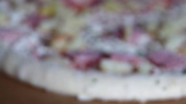 Donmuş Hawai pizzası, düşük açılı, yakından bakınca ananas dilimleri, jambon ve fast food sobası için hazır lezzetli otlar, yağlı peynirli hazır yemekle birlikte sağlıksız yemek için ev yapımı yemekler gösteriyor.
