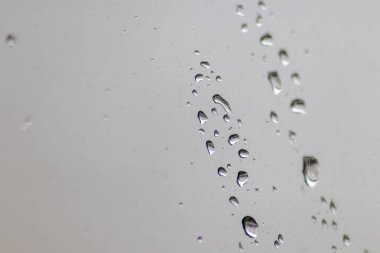 Sonbahar ve sonbahar sezonu için gevşetici arka plan dokusu olarak pencereye yağmur damlaları ve yağmur damlacıklarının depresyon havasında yağmurlu hava dokusu ile pencere yüzeyine sıçradığını gösteriyor