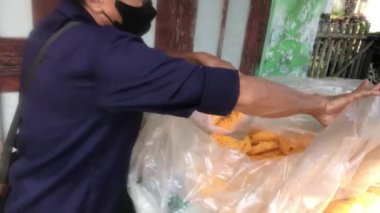 Bir adam müşterisinin krakerlerini plastik bir torbaya koyuyor..