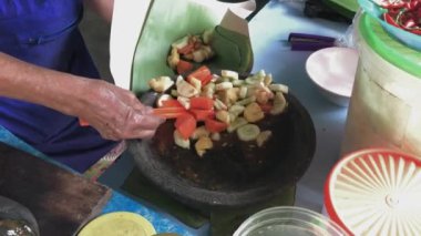 Evde geleneksel sağlıklı salata (rujak buah) yapmak için kağıt taze meyve ile karıştıran ve saran kadın.