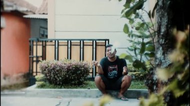  Bir adam cep telefonu tutarken ve elinde sigara taşırken rahatlıyor..