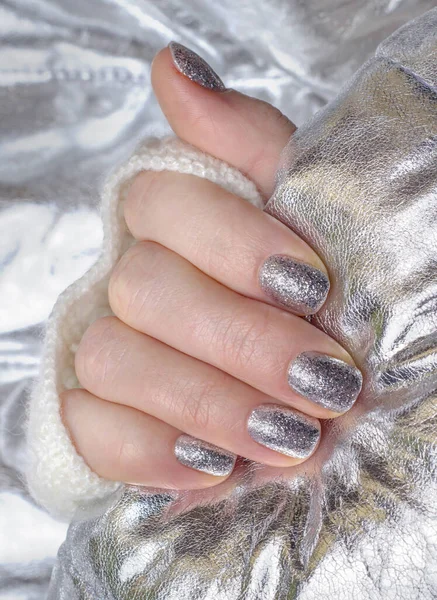 Manicure with silver sequins on a silver background.