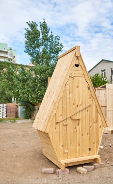 Sıradan bir şehrin ortasında ahşap bir tuvalet duruyor.