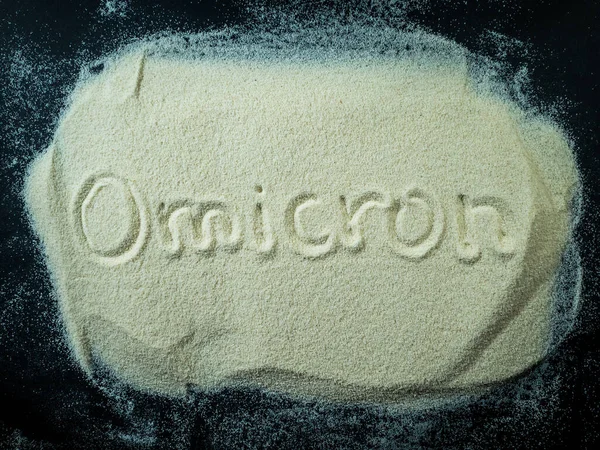 Omicron siyah arkaplanlı beyaz kumun üzerine yazıldı