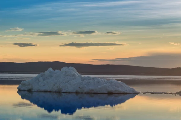 The melting iceberg on spring mountain lake in the setting sun. — Stock Photo, Image