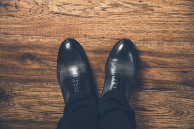 Ahşap arka planda ayakkabıları olan bir adam