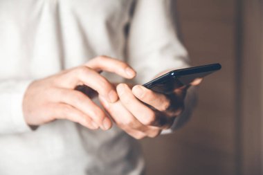 Genç adam elinde akıllı telefon tutuyor.
