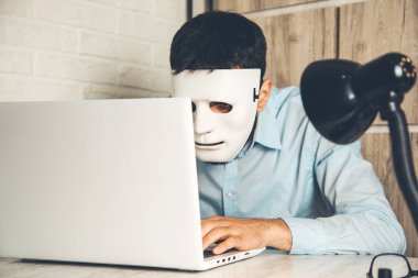 Masasında bilgisayar olan adam maskesi.