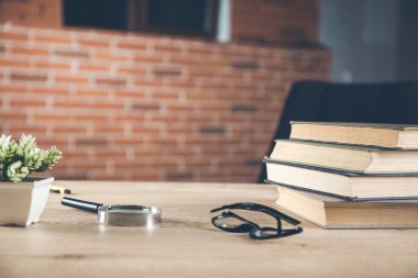 Masanın üzerinde kitaplar olan büyüteç.