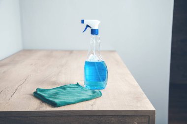 Masanın üzerinde mavi sprey sprey ve kumaş temizleme.