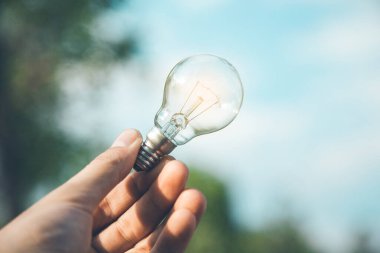 Adam gökyüzünde ampulü tutuyor.