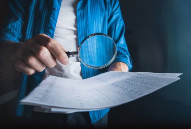 Koyu arkaplanda büyüteçle insan eli belgesi