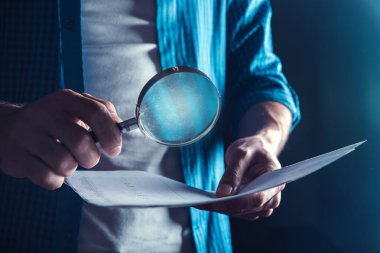 Koyu arkaplanda büyüteçle insan eli belgesi