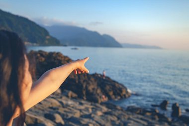 Kadın parmak günbatımında denizi gösterir