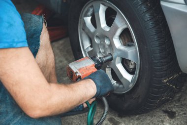 Araba tamircisi araba tekerleğini beceriyor. 