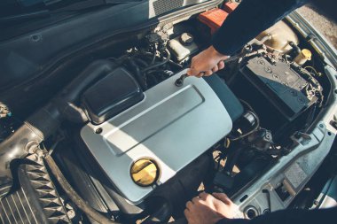 Adam araba motorunda çalışıyor.