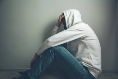 Üzgün adam kafa kafaya oturuyor.