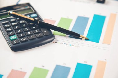 Hesap makinesi ve kalem masanın üstünde.