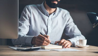 Masasında bilgisayar olan bir not defteri.