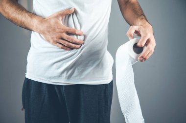 Gri arka planda tuvalet kağıdı tutan adam.