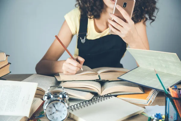 woman hand smart phone with books on desk