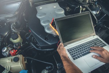 man to repair car with hand computer