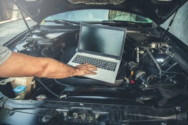 man to repair car with hand computer