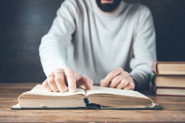 man reading book on the wooden desk