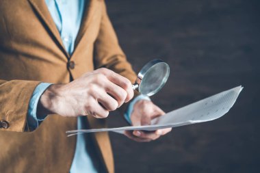 man hand magnifier with document on dark background