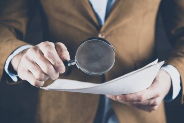 man hand magnifier with document on dark background