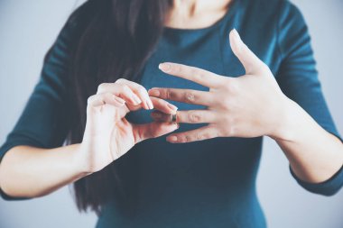 woman remove ring on gray background