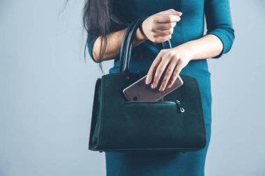 woman hand phone with bag on gray background