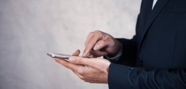 Adam gri arka planda akıllı telefonu tutuyor.