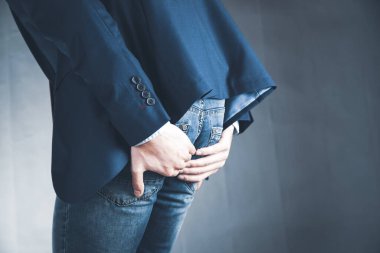 Gri renkte izole edilmiş, acı içinde kıçını tutan adam.