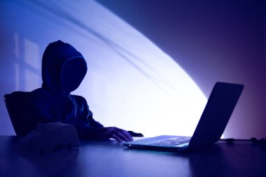 Karanlık arka planda bilgisayarı olan bir hacker.