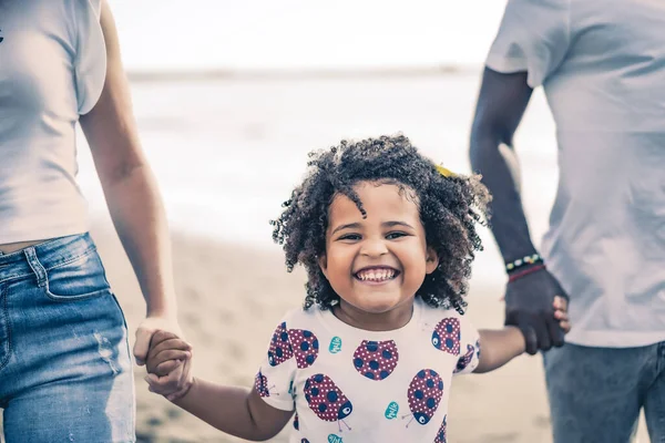 年轻夫妇和他们的女儿在海滩散步 享受一天的时光 儿童的近视 假日和家庭的概念 图库照片