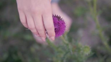 Kız çiçeğe nazikçe eliyle dokunur.