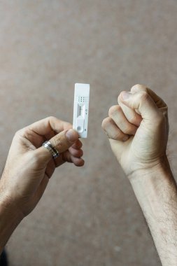 Negatif sonuç alan Covid-19 testini geçtikten sonra sevinen tanınmayan kişi elinde negatif antijen testi tutarken sevinir.