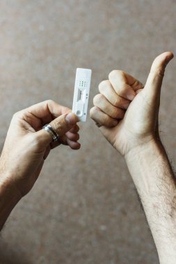 Negatif sonuç alan Covid-19 testini geçtikten sonra sevinen tanınmayan kişi elinde negatif antijen testi tutarken sevinir.